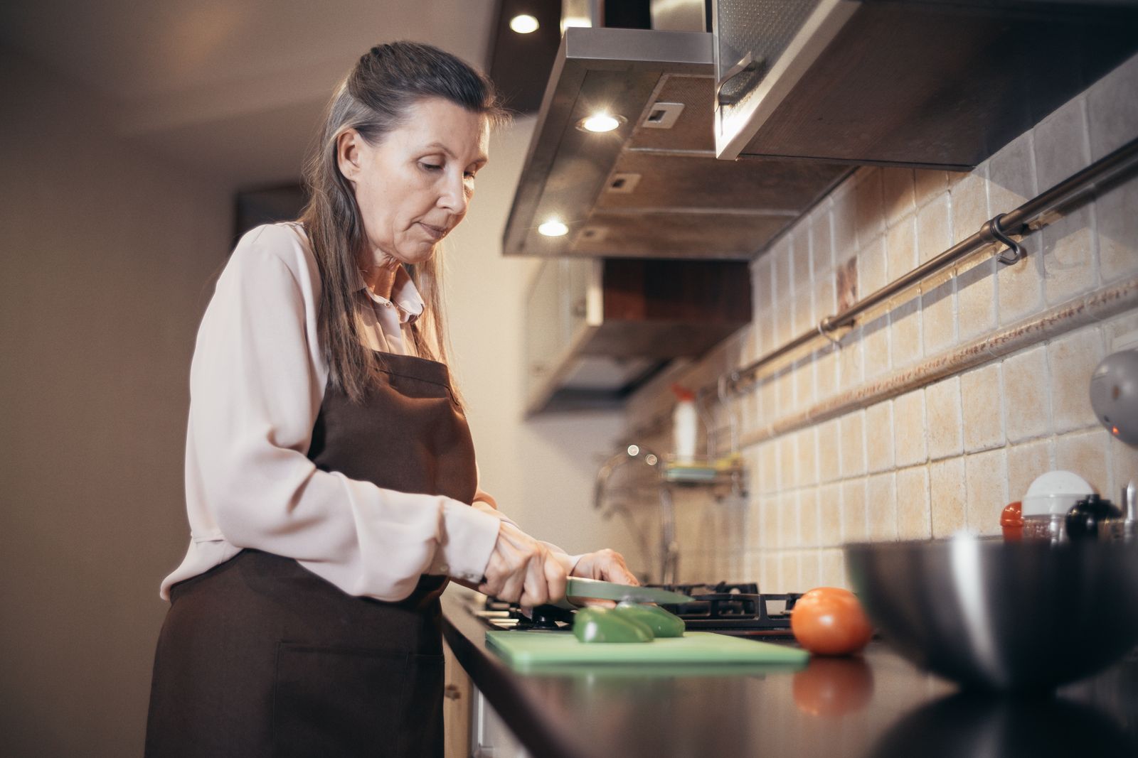An older woman preparing vegetables in her kitchen.