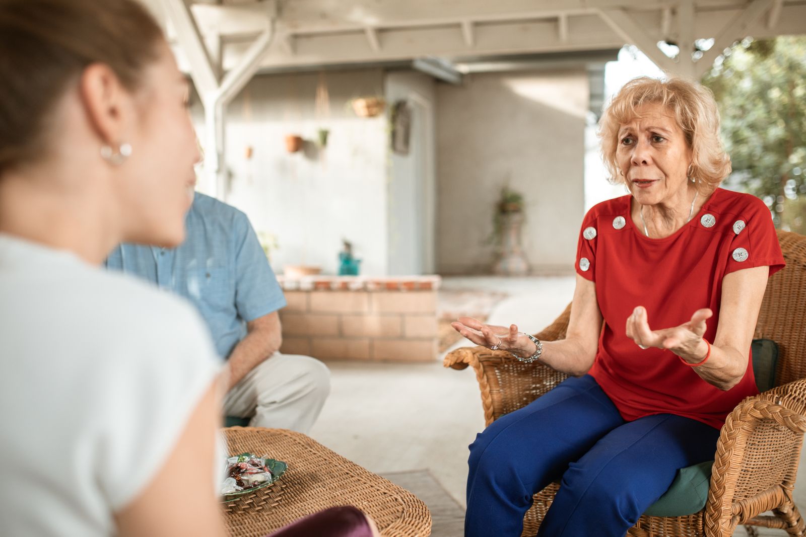 An older woman discussing everyday life with family on a porch.