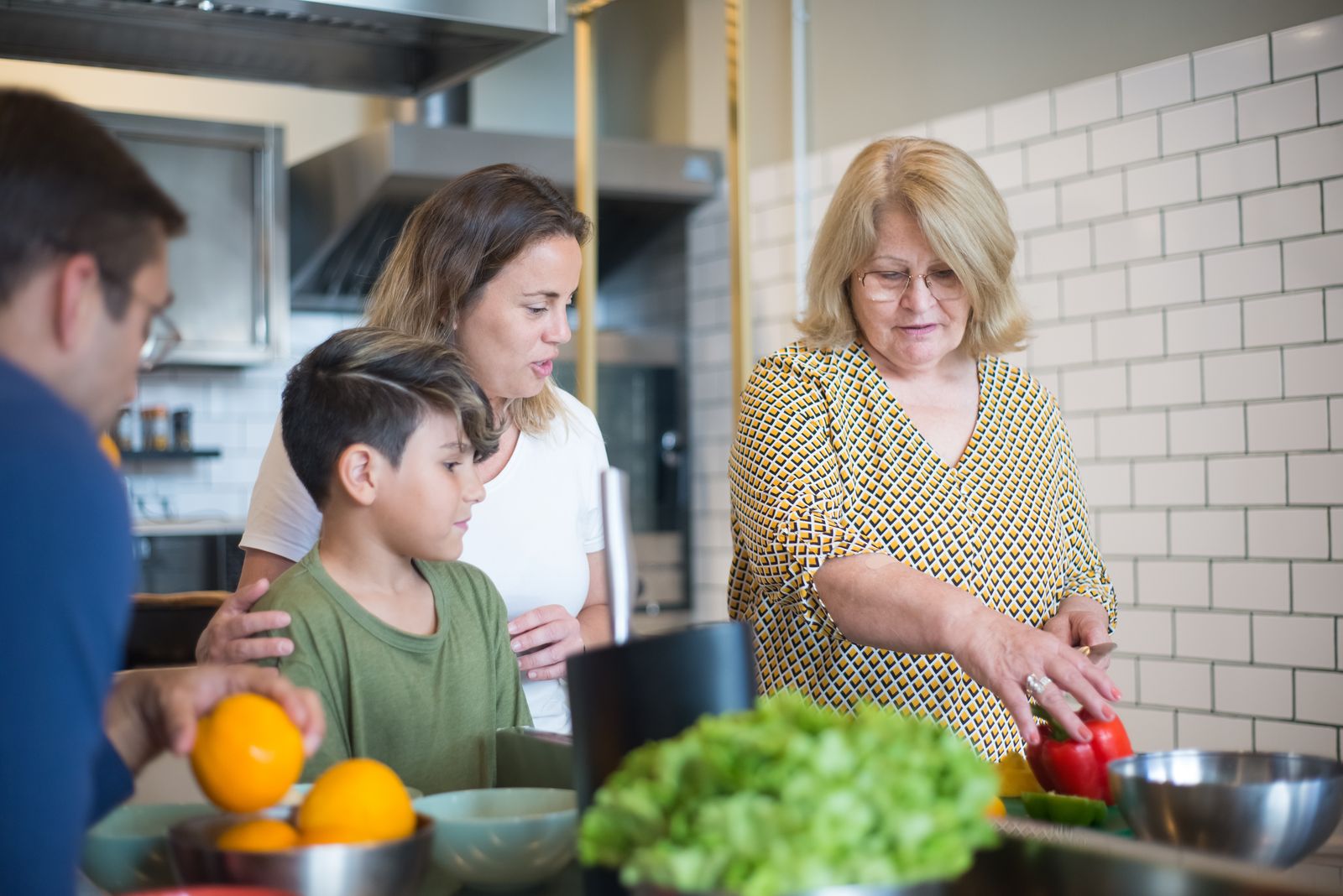 Three generations preparing vegetables together in a kitchen.